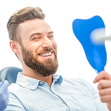 man with beard checking smile in blue mirror