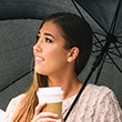 woman holding umbrella and coffee cup