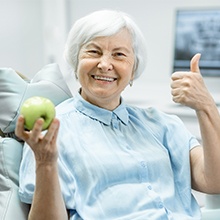 woman doing thumbs up and holding green apple