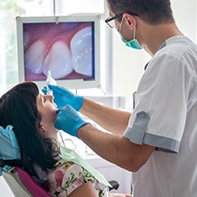 dentist using intraoral camera in woman's mouth